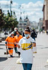 Young woman holding coffee wearing protective medical mask