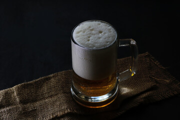 Mug with beer and foam on a dark background.