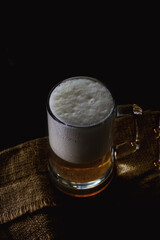 Mug with beer and foam on a dark background.