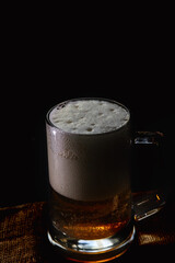 Mug with beer and foam on a dark background.