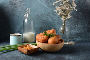 Tasty breakfast rustic style. Stuffed Buns (Pirozhki) ,milk,with green onions and Homemade pickled honey agarics mushrooms,and potatoes. Flowers at background - obrazy, fototapety, plakaty