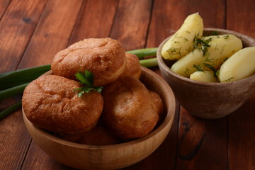 Stuffed Buns (Pirozhki) in wooden bowl on the wooden background. With green onions ,and herbs. Homemade pasty, Russian stuffed pastry.