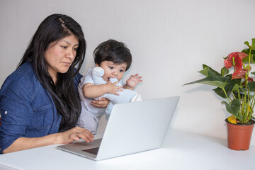 Mexican Mother working from home while her son distracts her and drawing attention