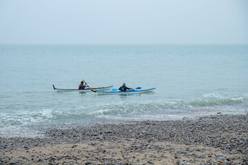Fototapeta na wymiar Two people Kayaking on the sea on a dark grey day