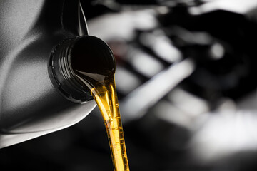 Pouring oil lubricant motor car from black bottle on engine background oil change auto shop