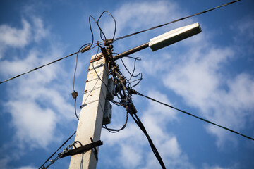 Close-up of power poles with wires on a blue sky with clouds.