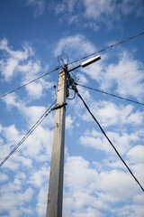 Close-up of power poles with wires on a blue sky with clouds.