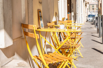A row of empty yellow tables in a street cafe on a sunny morning. Vertical.