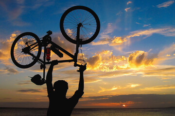 Ciclista levantando uma bicicleta sobre a cabeça.
