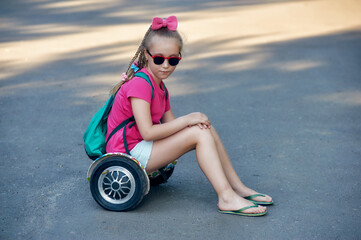 A little girl is resting sitting on a hoverboard . The concept of environmental transport for the...