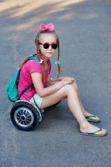 A little girl is resting sitting on a hoverboard . The concept of environmental transport for the...