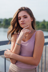 Pretty young woman posing on the old rusty transport bridge over the river during sunset.