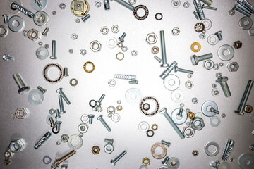 different sizes of various screws, bolts, nuts on grey metal background. fixing elements for home work or DIY