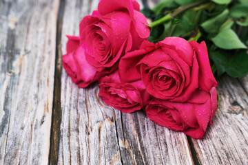 A bouquet of five red roses on a wooden background