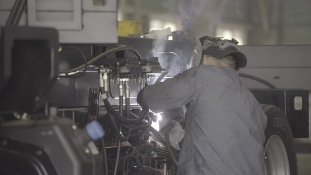worker welding complex machine in factory