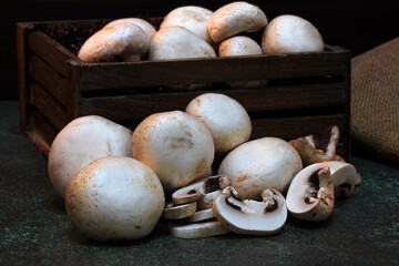 White button mushrooms stacked in front of a crate.