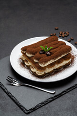 Classic tiramisu dessert on ceramic plate on concrete background