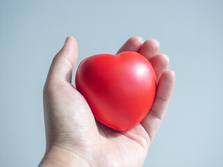 Red heart. Big red heart ball in hand on grey background.