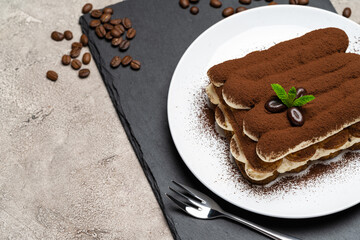 Classic tiramisu dessert on ceramic plate on concrete background