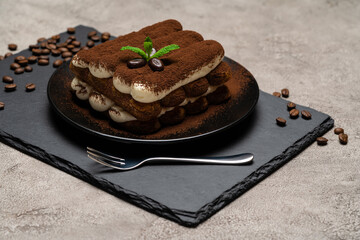 Classic tiramisu dessert on ceramic plate on concrete background