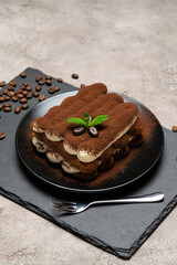 Classic tiramisu dessert on ceramic plate on concrete background