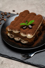 Classic tiramisu dessert on ceramic plate on concrete background