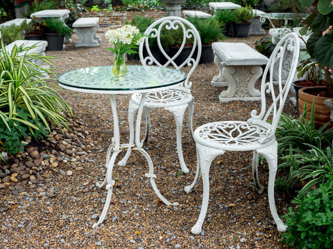 White Wrought Iron Table With White Flower In Vase On Glass Top And Chair Vintage Style.