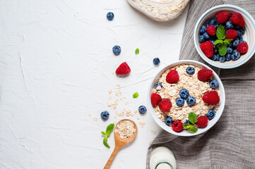 Breakfast, oatmeal with blueberry and raspberry on white bowl in the morning.