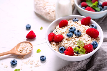 Breakfast, oatmeal with blueberry and raspberry on white bowl in the morning.