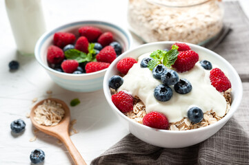 Breakfast, oatmeal with blueberry and raspberry on white bowl in the morning.