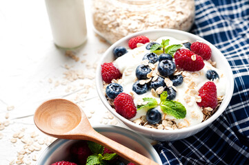 Breakfast, oatmeal with blueberry and raspberry on white bowl in the morning.