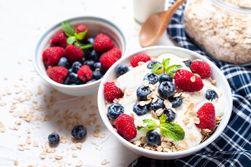 Breakfast, oatmeal with blueberry and raspberry on white bowl in the morning.