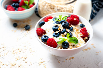 Breakfast, oatmeal with blueberry and raspberry on white bowl in the morning.