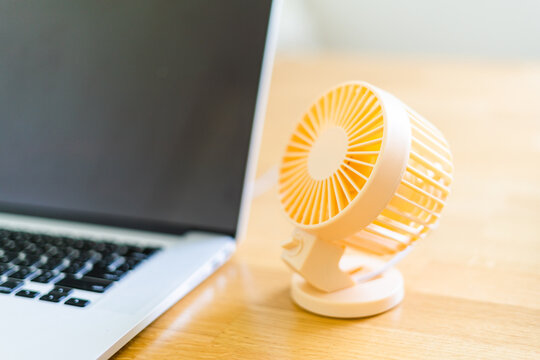 Mini usb fan near laptop. Summer office day. Mini portable cooler