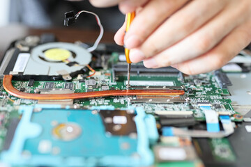 Worker is repairing to inside the laptop. The basic components of laptops function identically to their desktop counterparts. Traditionally they were miniaturized and adapted to mobile use.