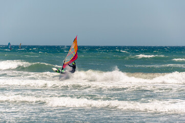 A windsurfer rides the waves in the Mediterranean on a windy and sunny day.