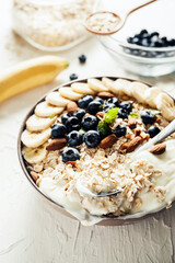 Breakfast, oatmeal with blueberry, banana almond and yogurt on a bowl in the morning.