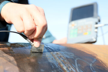 Inspector is testing of the steel pipe welds with ultrasonic test method. It is a non-destructive test method. It can also be used to determine a material's thickness, such as measuring the wall.