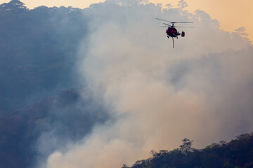 Fototapeta na wymiar Firefighting helicopter dropping water on forest fire