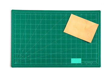 Green grid cutting matt or pad with color paper note on background.