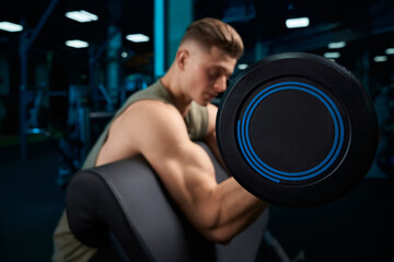 Fototapeta na wymiar Muscular man building biceps with barbell.