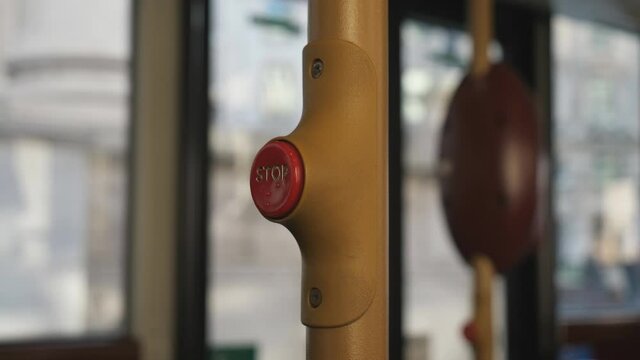 A close-up view of a 'stop' button on a bus rail.