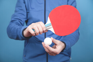 Man holding tennis racket and white plastic ball.