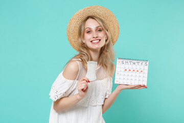 Smiling young woman girl in white dress hat hold periods calendar for checking menstruation days sanitary napkin isolated on blue turquoise background studio. Medical healthcare gynecological concept.