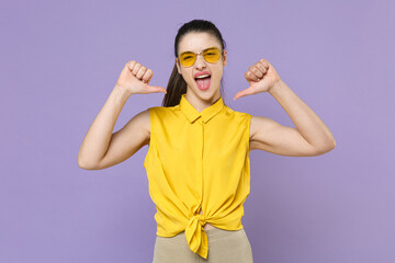 Screaming young brunette woman girl in yellow casual shirt posing isolated on violet wall background studio portrait. People emotions lifestyle concept. Mock up copy space. Pointing thumbs on herself.