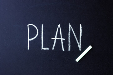 the word plan is written in white chalk on a black surface