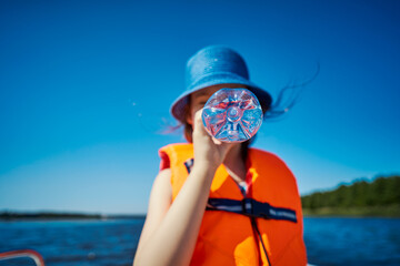 blurry little girl hides her mouth behind a bottle on a motorboat