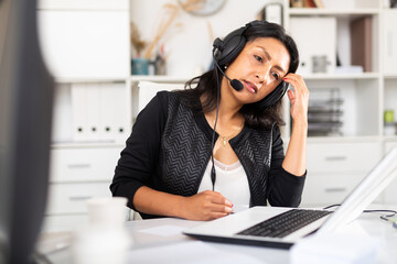 Weary woman with microphone headset at work in office