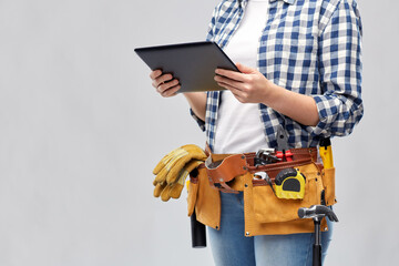 repair, construction and building concept - woman or builder with tablet pc computer working tools on belt over grey background