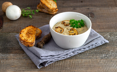 Delicious mushroom cream soup with toast close-up on the wooden table.